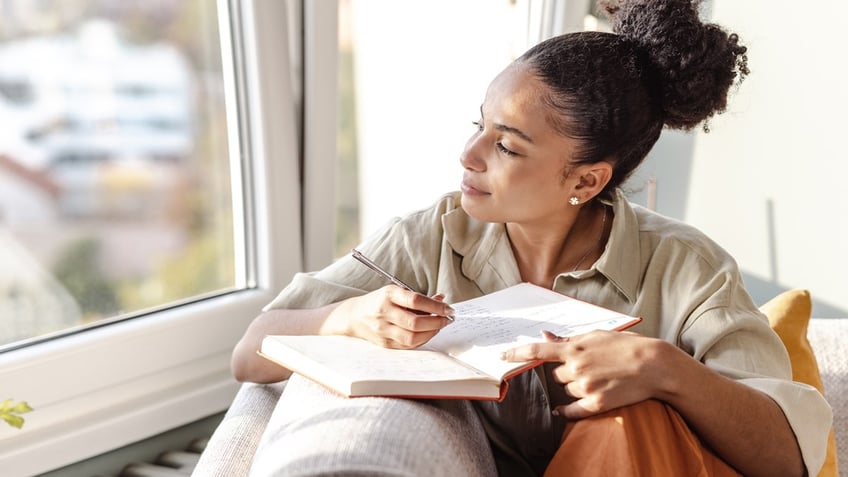 A woman journaling by the window