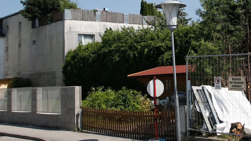 Building materials stand in the garden of the house of Josef Fritzl, who kept his daughter captive for 24 years and fathered seven children in the cellar, in the village of Amstetten June 21, 2013. The cellar is being sealed off with concrete, much to the relief of neighbours keen to forget one of Austria's most horrific crimes. Fritzl, was sentenced in 2009 to life imprisonment in a special unit for the criminally insane for incest, rape, coercion, false imprisonment, enslavement and for the negligent homicide of one of his infant sons.