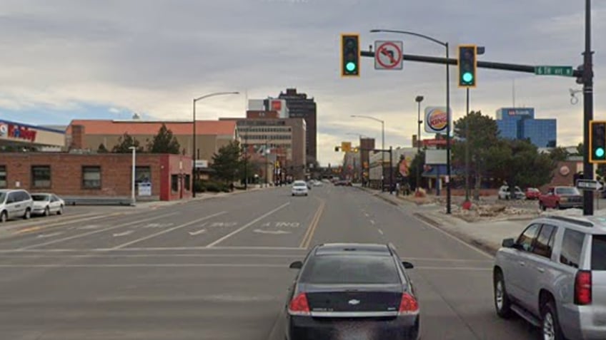 Back of cars driving through a green light at an intersection near Burger King and a gas station