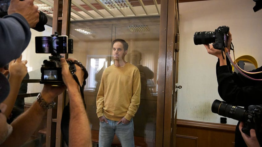 Wall Street Journal reporter Evan Gershkovich stands in a glass cage in a courtroom in Moscow, Russia