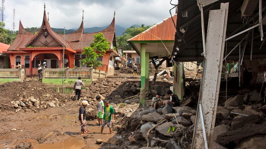 People inspect buildings damaged by a flash flood in Agam, West Sumatra, Indonesia