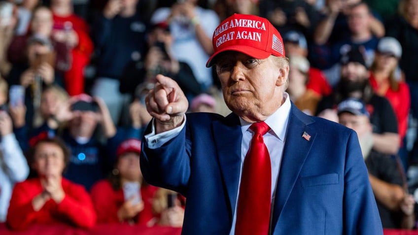 Donald Trump pointing, wearing red MAGA hat