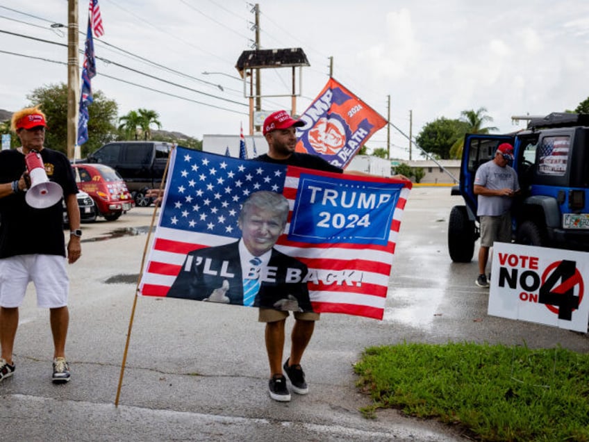 Supporters of the former US President Donald Trump hold signs prior to the kickoff of the