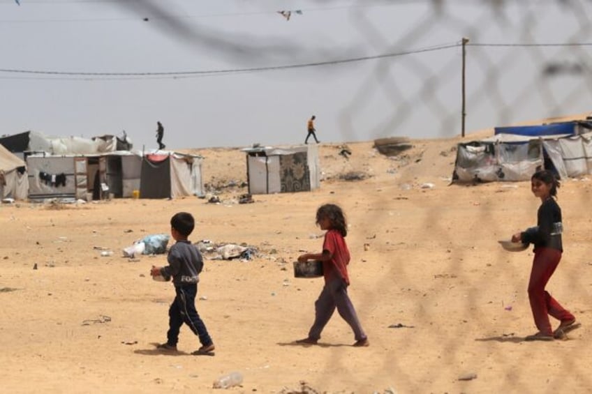 Displaced Palestinian children carry containers with food in Rafah on May 19, 2024, amid t