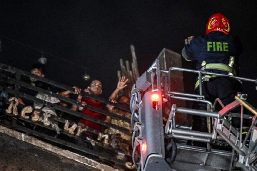 Firefighters use a fire ladder to extract victims during rescue operations following a fir