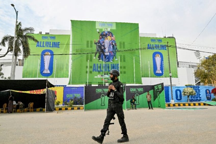 A Pakistani police commando walks past posters displayed ahead of the Champions Trophy in