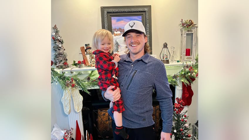 Morgan Wallen holds his son Indigo in front of Christmas decorations