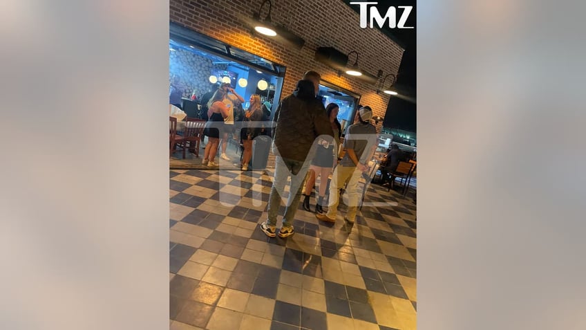 morgan wallen talking with a woman on a rooftop standing next to a table wiht three chairs