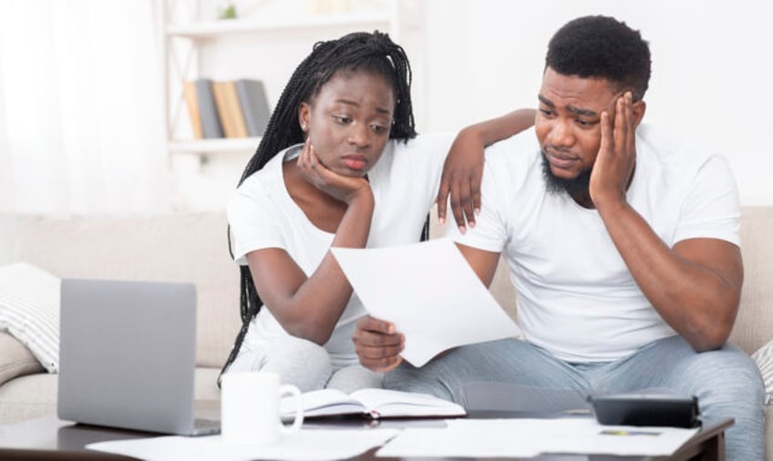 Debt concept. Portrait of sad afro couple looking at invoice, upset about huge bills, not
