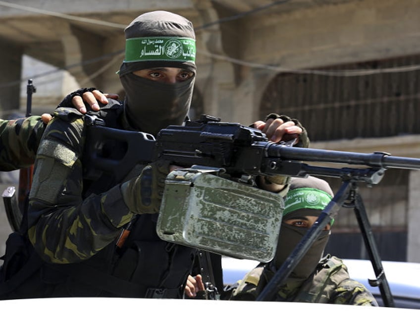 A masked militant from the Izzedine al-Qassam Brigades, a military wing of Hamas, stands b