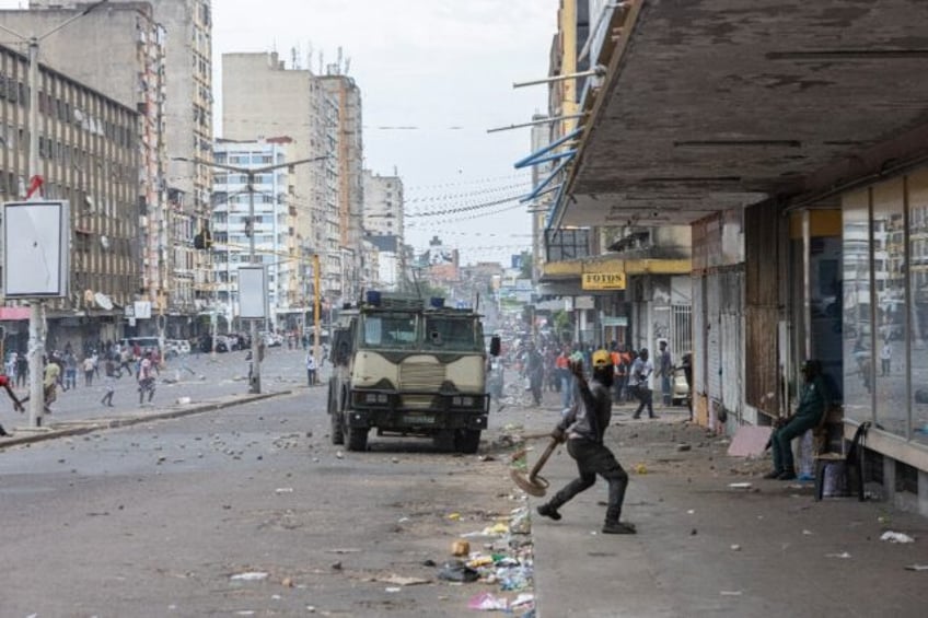 A protester throws a stone at an armoured vehicle during clashes in Mozambique's capital M