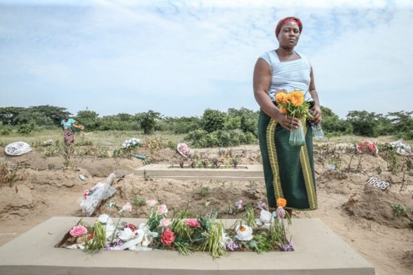 Ana Madivage brings flowers to the grave of her son killed in post-election violence in Mo