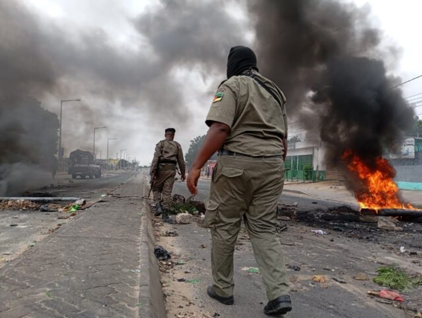 Mozambican security forces next to a burning barricade in Maputo on Tuesday, the second da