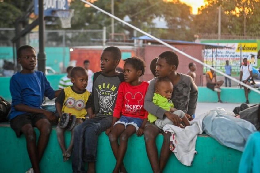 Children sit in a public square in the Port-au-Prince suburb of Clercine on November 15, 2023 after fleeing their home in a violent slum area amid gang clashes