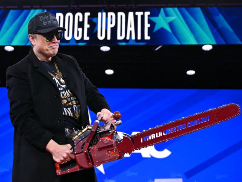 Elon Musk holds a chainsaw reading "Long live freedom, damn it" during the annua