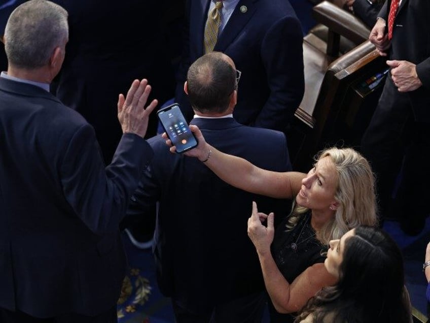 Rep.-elect Matt Rosendale (R-MT) (L) refuses to talk with former President Donald Trump on a phone being offered by Rep.-elect Marjorie Taylor Greene (R-GA) during the last moments of a contentious debate on the fourth day of voting for a new Speaker of the House at the U.S. Capitol Building …