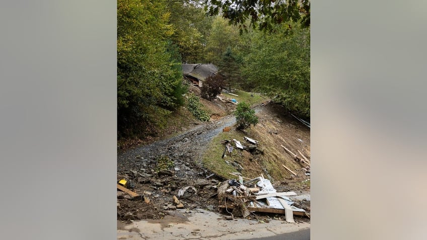 A destroyed home slopes on a steep, gravel road