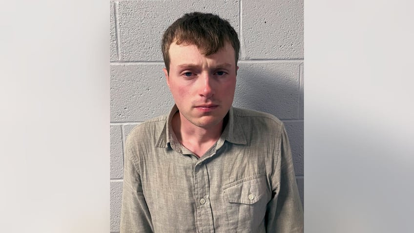 Logan Clegg in a button-down shirt near cement wall in mugshot