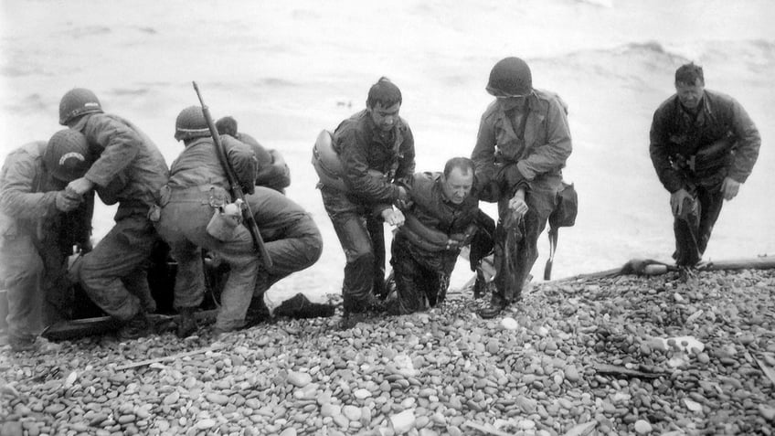 Soldiers carry troop onto beach during D-Day