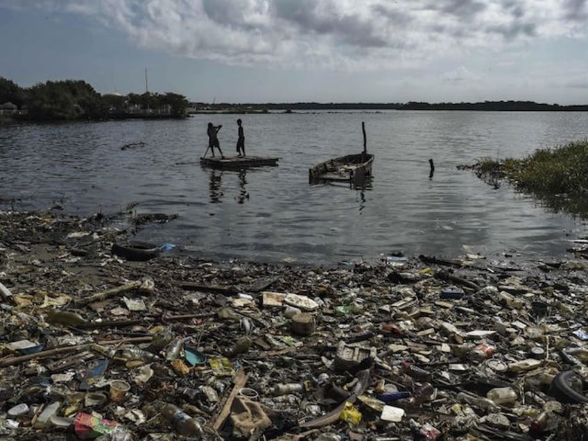 Children sail on a raft in the polluted waters of the Maracaibo Lake, in Maracaibo, Zulia state, Venezuela, on June 13, 2019. - The city of Maracaibo is the center of the country's oil industry, and its lake is an eternal oil spill. (Photo by YURI CORTEZ / AFP) (Photo by YURI CORTEZ/AFP via Getty Images)