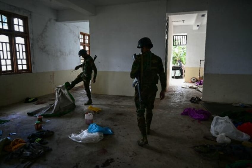 Members of the ethnic minority armed group Ta'ang National Liberation Army walk through a building at a hill camp seized from Myanmar's military in Namhsan