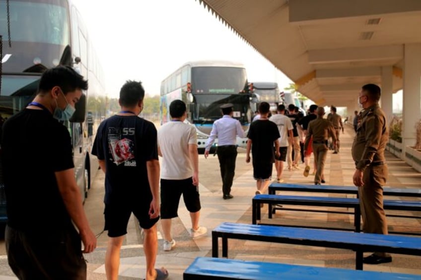 Alleged scam centre workers and victims from China arrive at the border checkpoint with Th