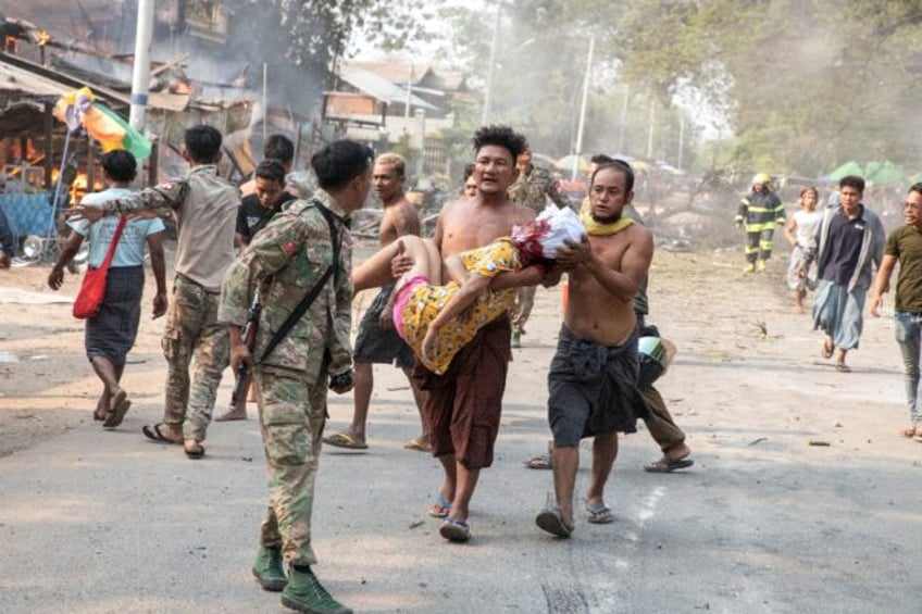 An injured civilian being carried following aerial bombardment of Singu in central Myanmar