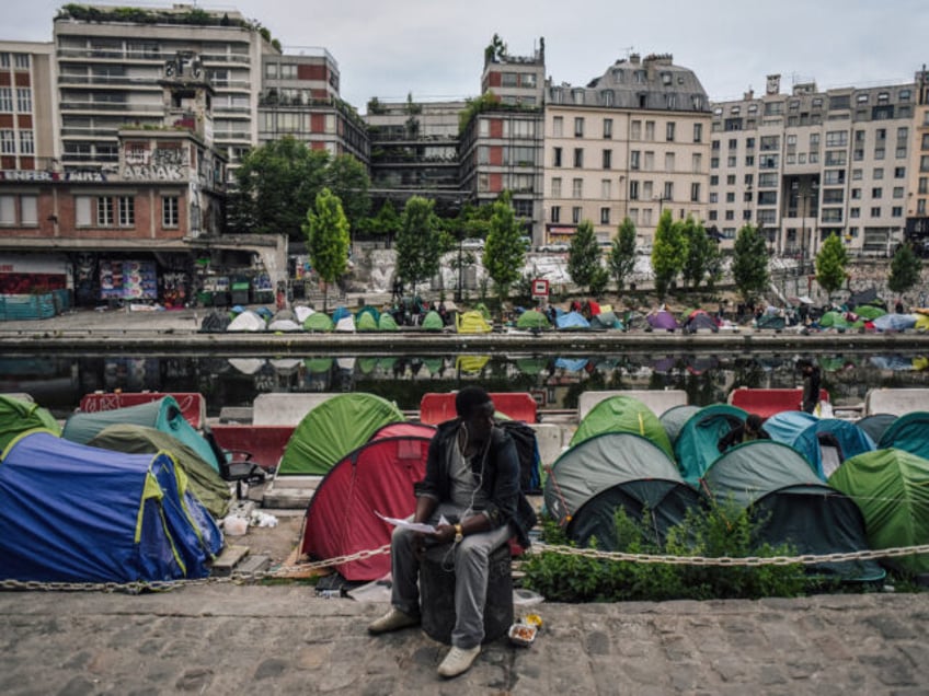 TOPSHOT - A man sits as migrants prepare their belongings at the start of the evacuation b
