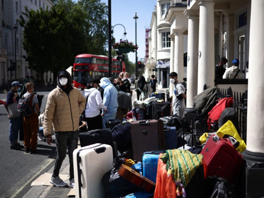 A group of migrants with their luggage, stage a protest outside their accomodation in west