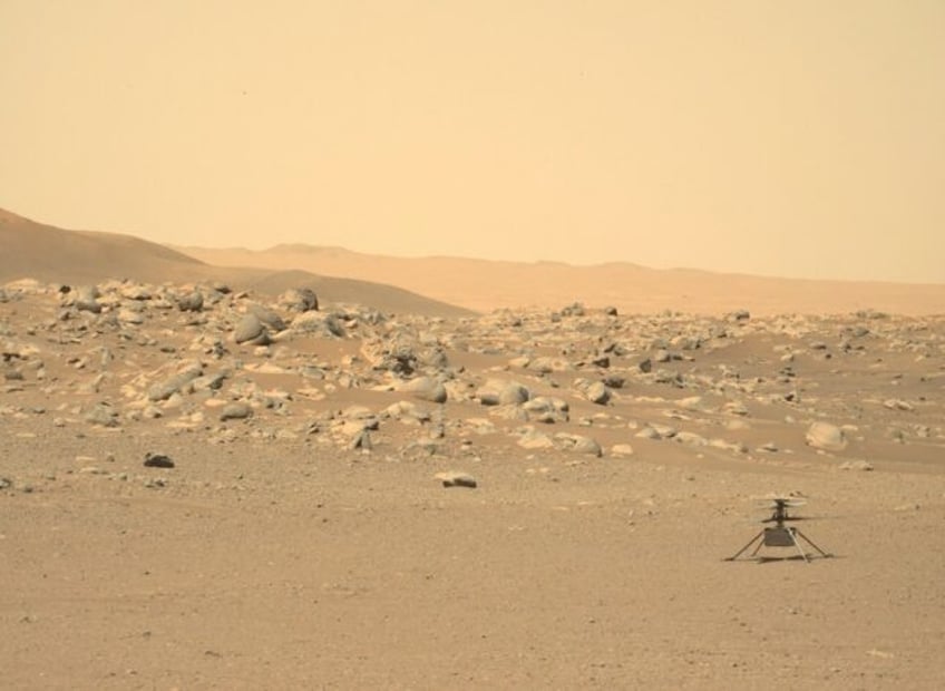 NASA's tiny Ingenuity helicopter is seen sitting on the surface of Mars in a photograph taken by the rover Perseverance