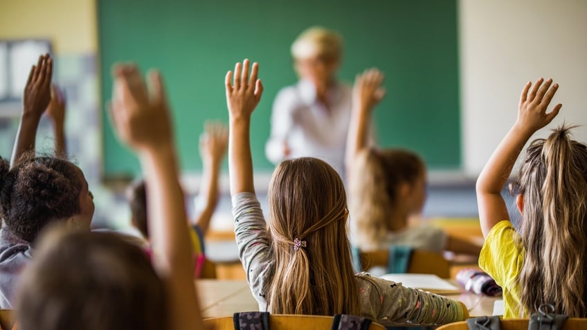 kids raising hands in classroom