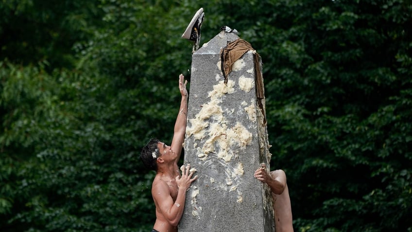 Naval midshipmen endeavor to climb the Herndon Monument to replace a white plebe 