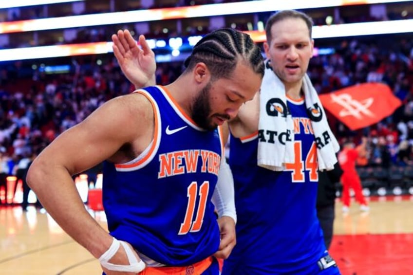 Jalen Brunson of the New York Knicks, front, hangs his head as he walks off the court foll