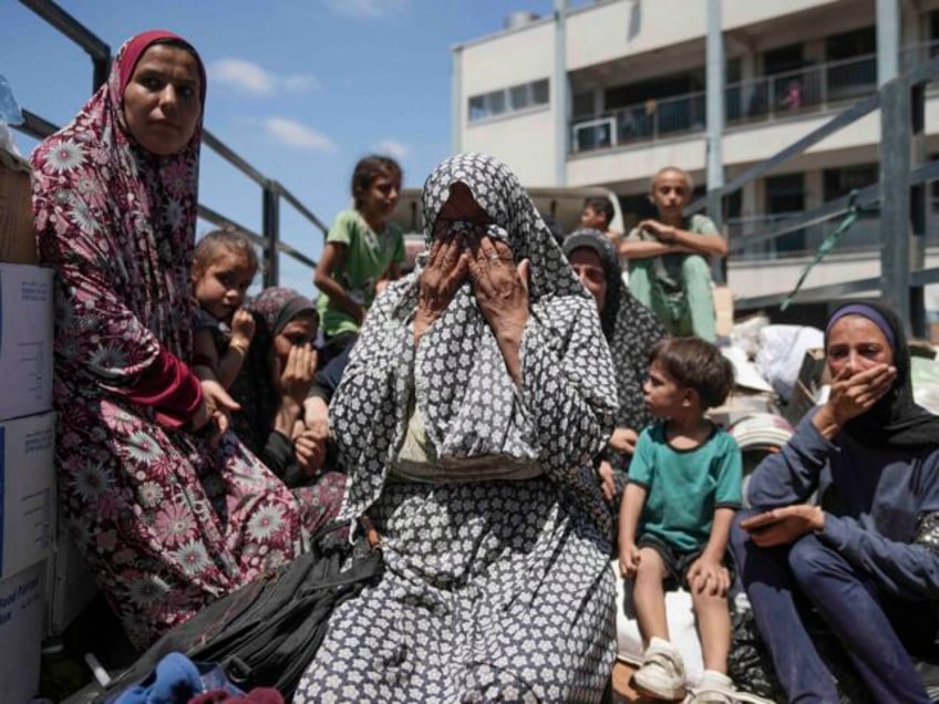 Palestinian women weep on a truck as she evacuates a school that had been her shelter, in