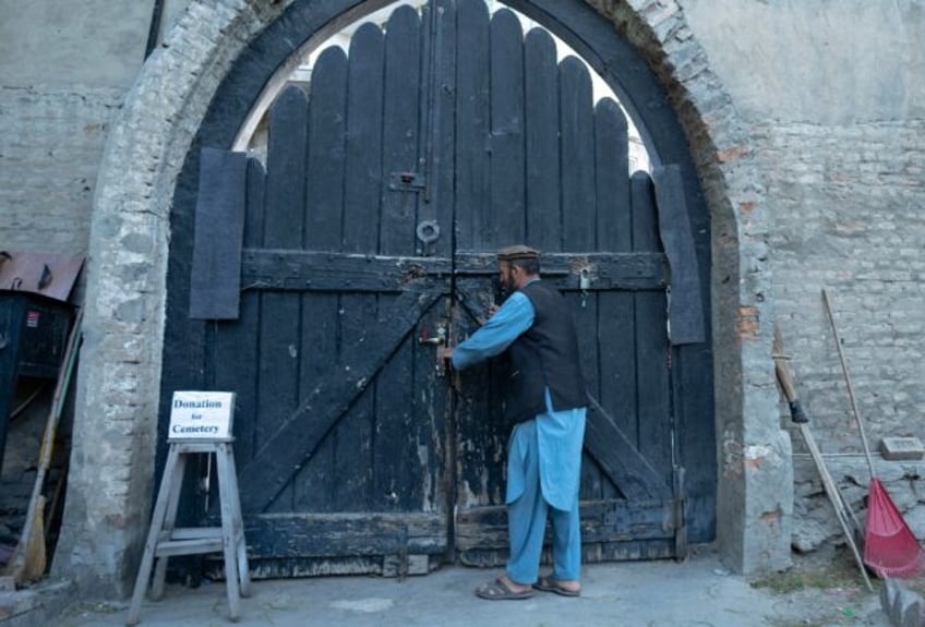 Gravekeeper Aynullah Rahimi unlocks a door at the British Cemetery in the Sherpur neighbou