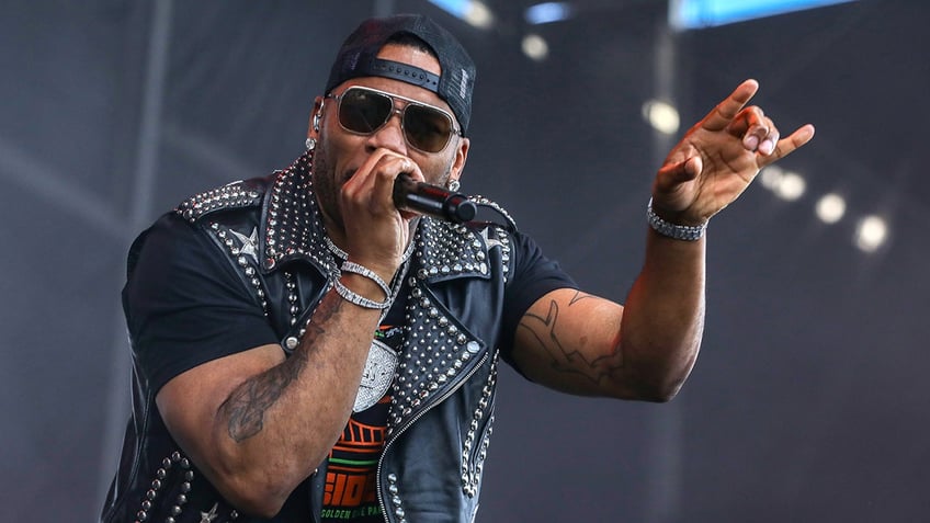 Nelly in a leather-studded vest points out into the crowd while performing on stage 