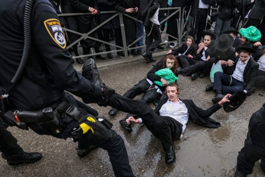 Israeli police officers try to remove ultra-Orthodox Jews protesting against defence minis