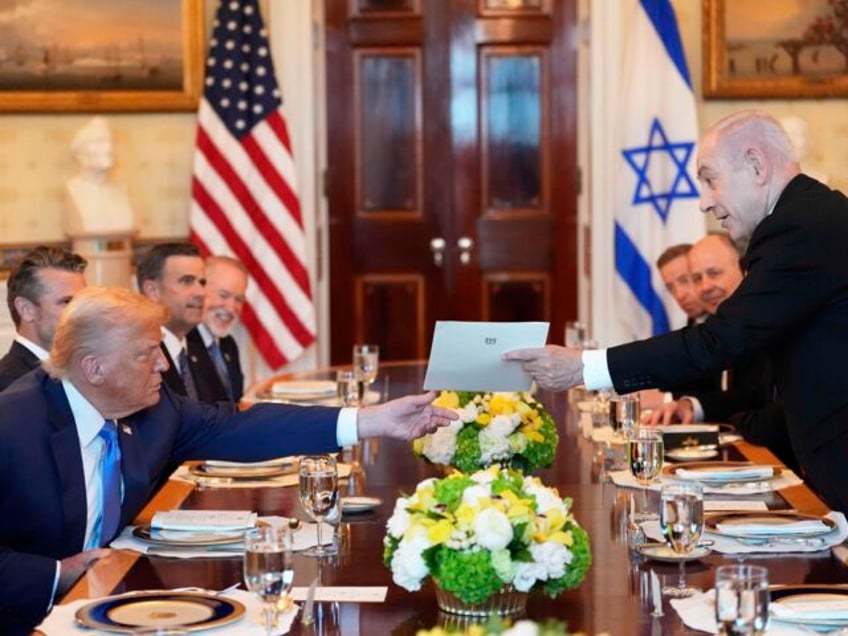 Israel's Prime Minister Benjamin Netanyahu, right, hands President Donald Trump a fol