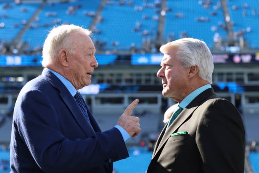 Dallas Cowboys owner Jerry Jones speaks with Jimmy Johnson before the game against the Carolina Panthers at Bank of America Stadium on November 19,...