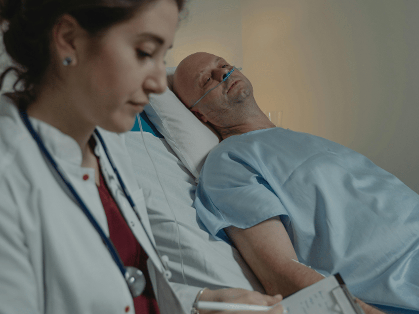 doctor writing on a medical chart with hospital patient