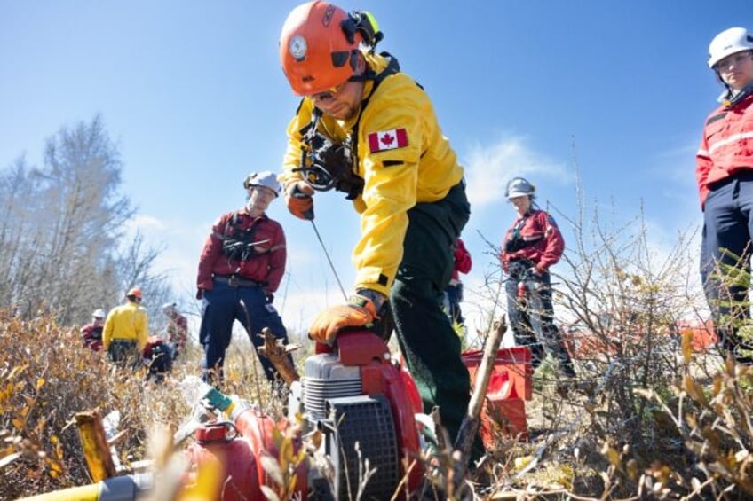 A Canadian firefighter in training in Quebec province practices using a motor-driven pump