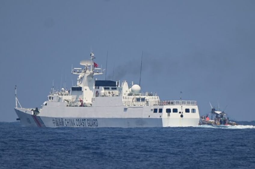 A China Coast Guard ship maneuvers past a Philippine fishing boat in the disputed South Ch