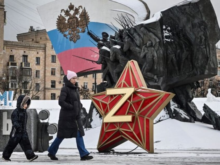 A woman and a child walk past a New Year decoration - Kremlin Star, bearing a Z letter, a insignia of Russian troops in Ukraine, in front of the Monument dedicated to Heroes of the WWI, in western Moscow, on December 26, 2023. (Photo by Alexander NEMENOV / AFP) (Photo …