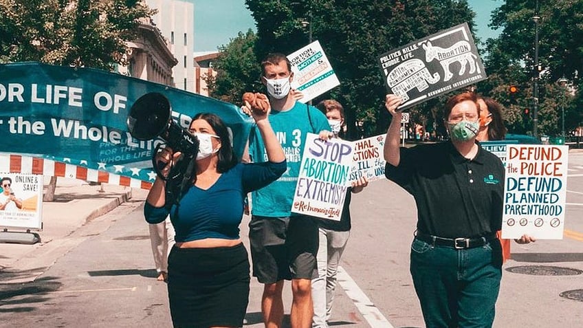Pro-life Democrats protest at the DNC in 2020. Terrisa Bukovinac shouts in a microphone with Matt Tuman, board chair of Democrats for Life of America, marching behind her and Herb Geraghty, executive director of Rehumanize International, at the right.