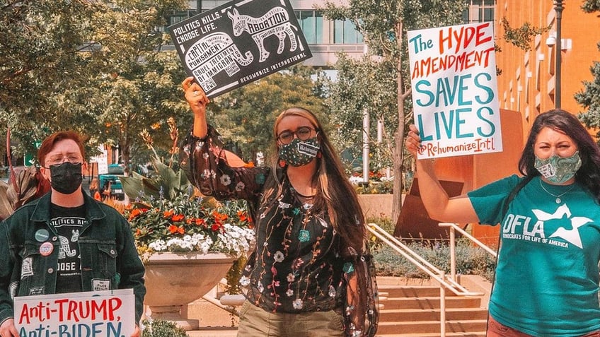 Herb Geraghty, executive director of Rehumanize International, protests with Maria Oswalt and Kirsten Vail, liberal pro-life activists. (Photo credit: Terrisa Bukovinac)