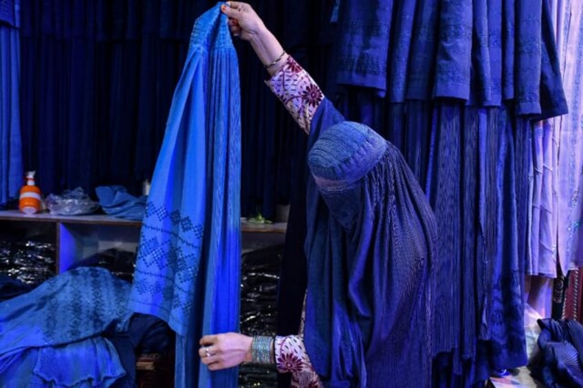 An Afghan shops in Mazar-i-Sharif: the all-enveloping blue burqa with a face mesh has beco