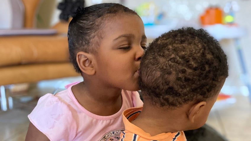 Big sister Sage kissing baby Sonny on the head.