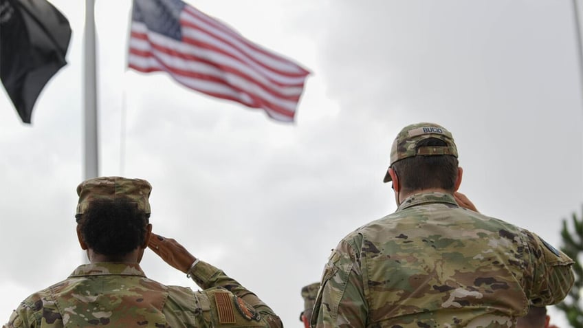 National Guard members salute the American flag