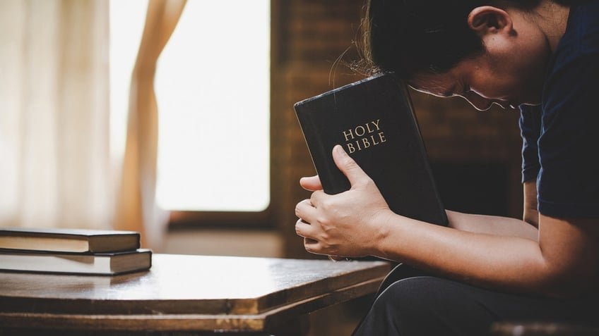 person praying with Bible in hands