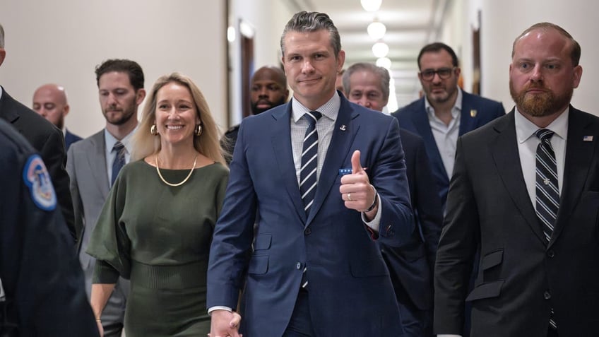 Pete Hegseth, President-elect Donald Trump's nominee to be Defense Secretary, gives a thumbs-up as he walks with his wife Jennifer Hegseth, left, to meet with Sen. Joni Ernst, R-Iowa, a member of the Senate Armed Services Committee, at the Capitol in Washington, Monday, Dec. 9, 2024. (AP Photo/J. Scott Applewhite)